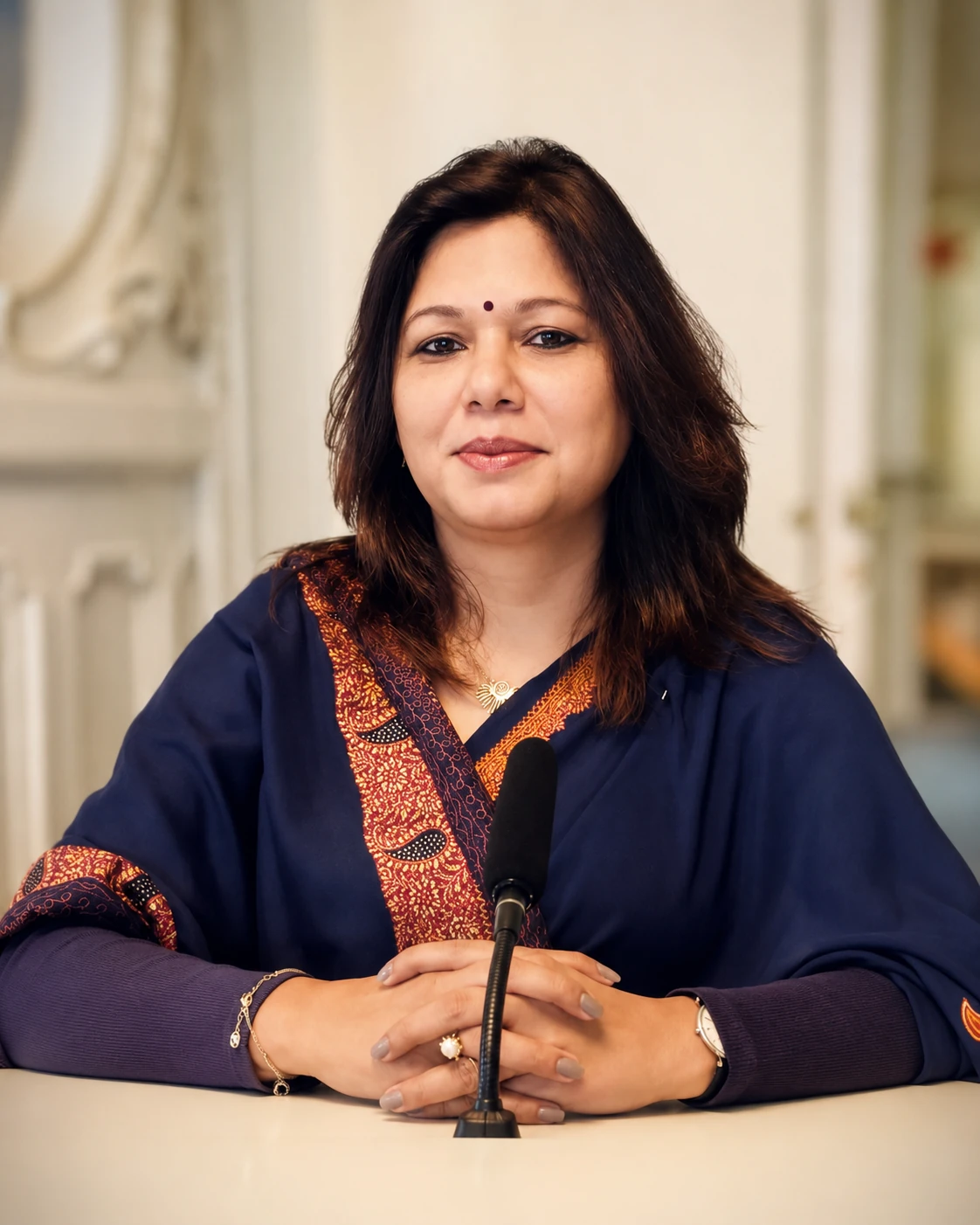 Shubhra Saxena seated at a microphone during an interview.